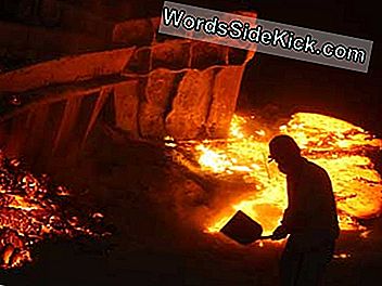 Pracovník zakrývá ocelovou strusku nalitou na zem písečnou zeminou v továrně na nerezovou ocel.