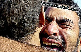 Иракский мужчина обнимает своего брата в ноябре 2005 года после того, как его освободили из тюрьмы Абу-Грейб, где американские военные связали заключенных, надели на них капюшоны и подвергли сексуальному унижению.